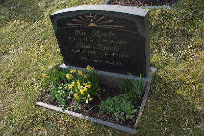 Gravminnet for Ola og Olga Bjørlo har også en reflekterende gravsten, samt at gravene er veldig tett i bratt terreng. Valgte å ta et bilde fra siden. Hovedsaklig kun refleksjon av blomster i stenen på bildet, og dette skaper ikke problemer ved avlesing.